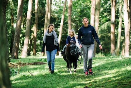 Pony mit Kind zwischen zwei Frauen